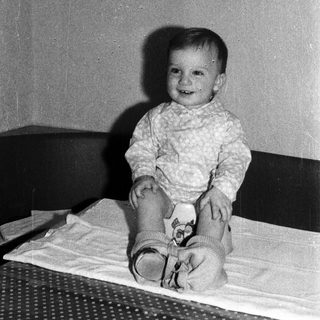 Baby smiling while sitting on a bed.