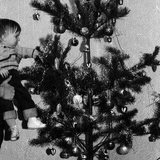 Child decorating a small Christmas tree with ornaments.