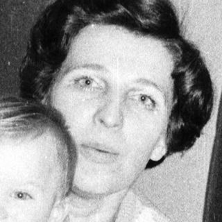 A woman holding a smiling young child indoors.