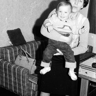 A woman holding a smiling young child indoors.