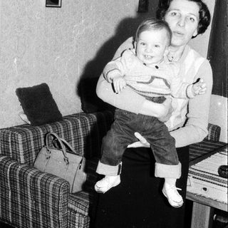 A woman holding a smiling young child indoors.