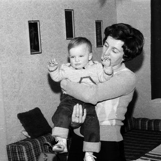 A woman holding a young child indoors.