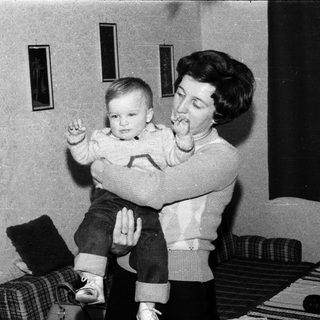 A woman holding a young child indoors.