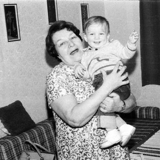 A woman joyfully holding a smiling toddler indoors.