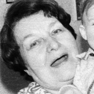 A woman joyfully holding a smiling toddler indoors.