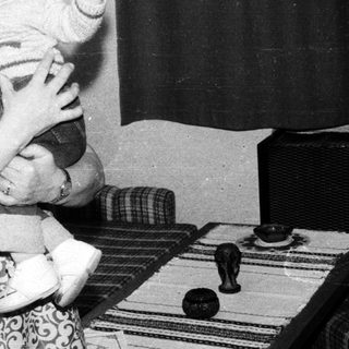 A woman joyfully holding a smiling toddler indoors.