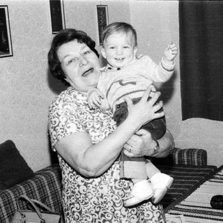 A woman joyfully holding a smiling toddler indoors.
