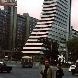 Two men walking near "Palacio del Estado" building.