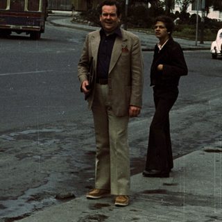 Two men walking near "Palacio del Estado" building.