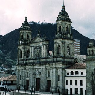 Baroque-style cathedral with twin towers, set against mountainous backdrop.