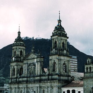 Baroque-style cathedral with twin towers, set against mountainous backdrop.