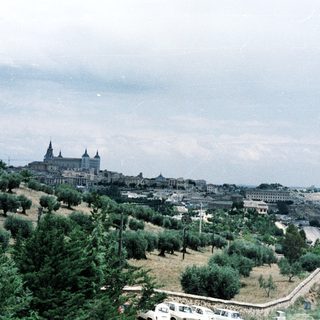 Historic city with cathedral atop hillside.