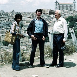 Three people posing outdoors near Madrid's Alcázar.