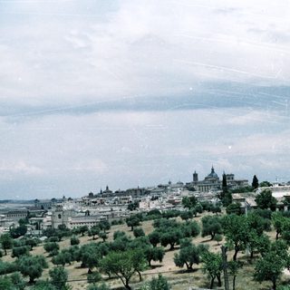 Historic cityscape with royal palace and green hills.