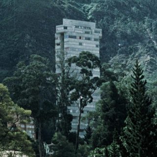 Urban park with hillside buildings and greenery.