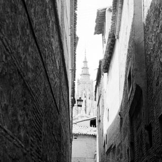 Narrow medieval street with tower in background.