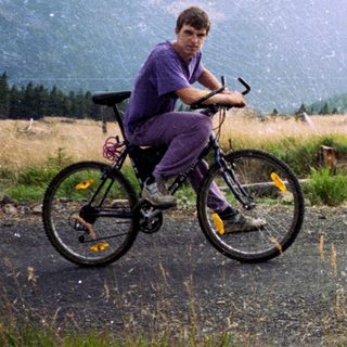 Person riding mountain bike in rural hilly landscape.