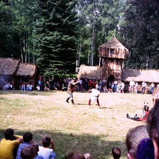 Traditional outdoor performance in rural setting with thatched structures.