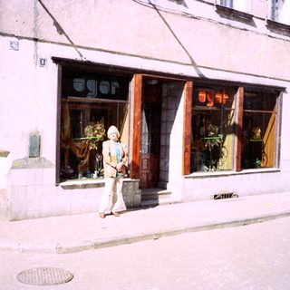 Woman standing outside a shop named "Agorá" on a city street.