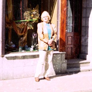 Woman standing outside a shop named "Agorá" on a city street.
