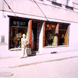 Woman standing outside a shop named "Agorá" on a city street.