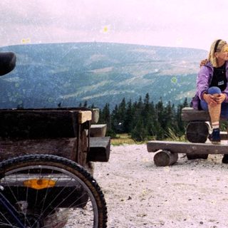 Couple sitting on picnic benches in mountainous outdoor area.