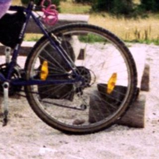 Two people sitting on bikes in mountainous outdoor area.