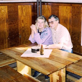 Two people sitting at wooden table indoors.