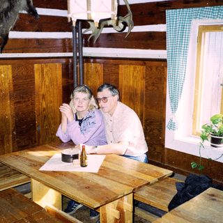 Two people sitting at wooden table indoors.