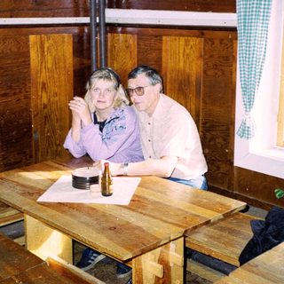 Two people sitting at wooden table indoors.