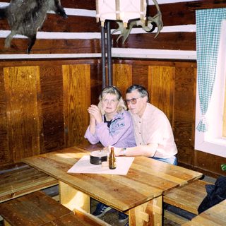 Two people sitting at wooden table indoors.