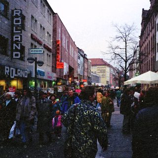 Busy city street with snowfall, crowded pedestrians.