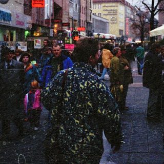 Busy city street with snowfall, crowded pedestrians.