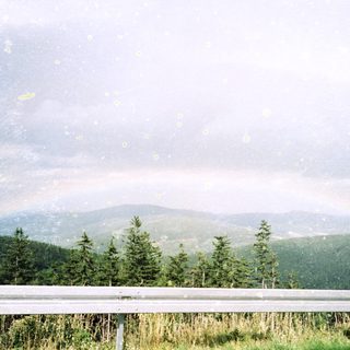 Scenic view of forested mountains under cloudy sky.