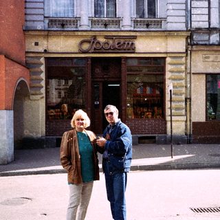 Two people posing outside a storefront