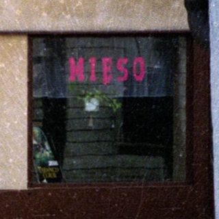 Two people posing outside a storefront