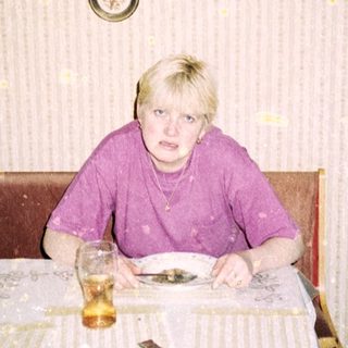 Person sitting alone at a table in a simple dining area.
