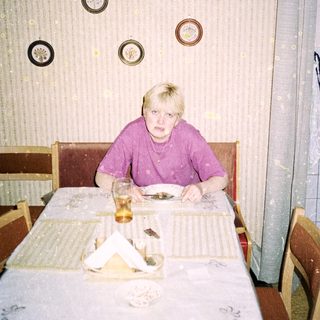 Person sitting alone at a table in a simple dining area.