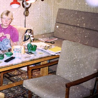 Child sitting indoors eating at cluttered table.