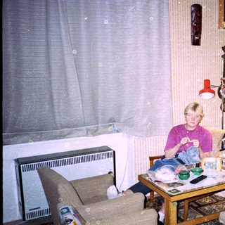 Child sitting indoors eating at cluttered table.
