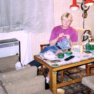 Child sitting indoors eating at cluttered table.