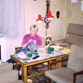 Child sitting indoors eating at cluttered table.