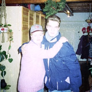 Two people posing indoors during winter holiday season.