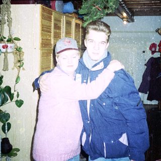 Two people posing indoors during winter holiday season.