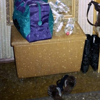 Woman standing by entrance with wrapped packages and shoes.