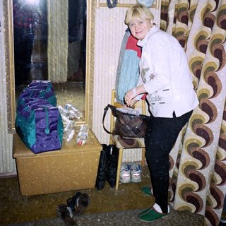 Woman standing by entrance with wrapped packages and shoes.