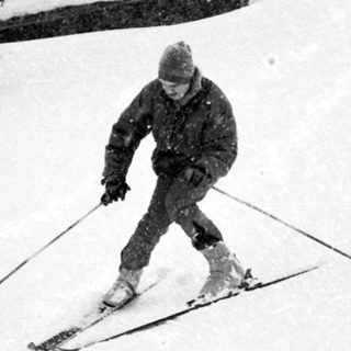 A skier descending snow-covered slope in winter.