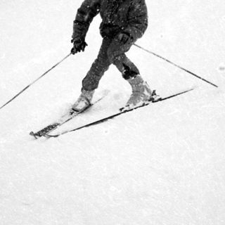 A skier descending snow-covered slope in winter.