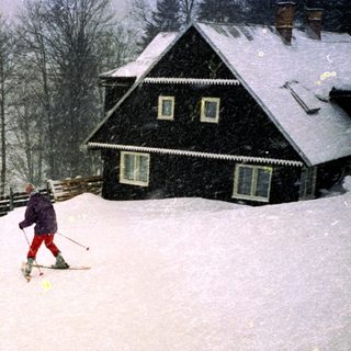 Skiier descending snow-covered slope in heavy snowfall.