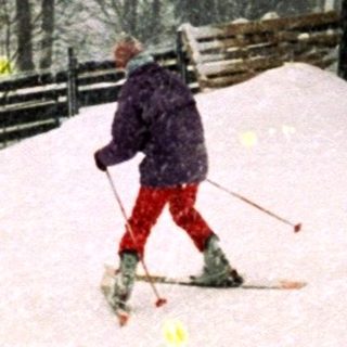 Skiier descending snow-covered slope in heavy snowfall.
